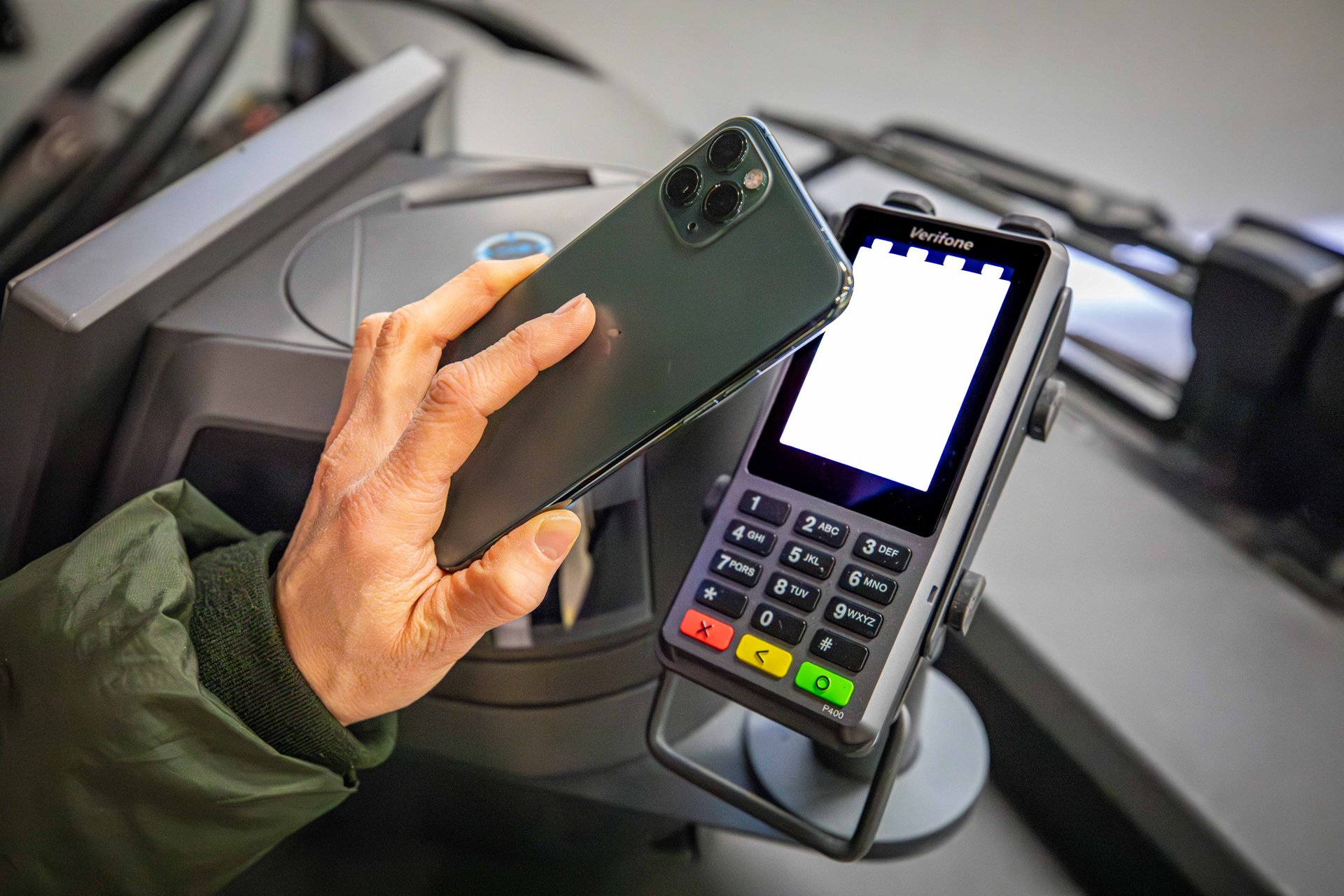 bargeldlos bezahlen in den Bussen der koveb Eine Hand mit Handy, das an ein Cashless-Payment-Terminal im Bus gehalten wird