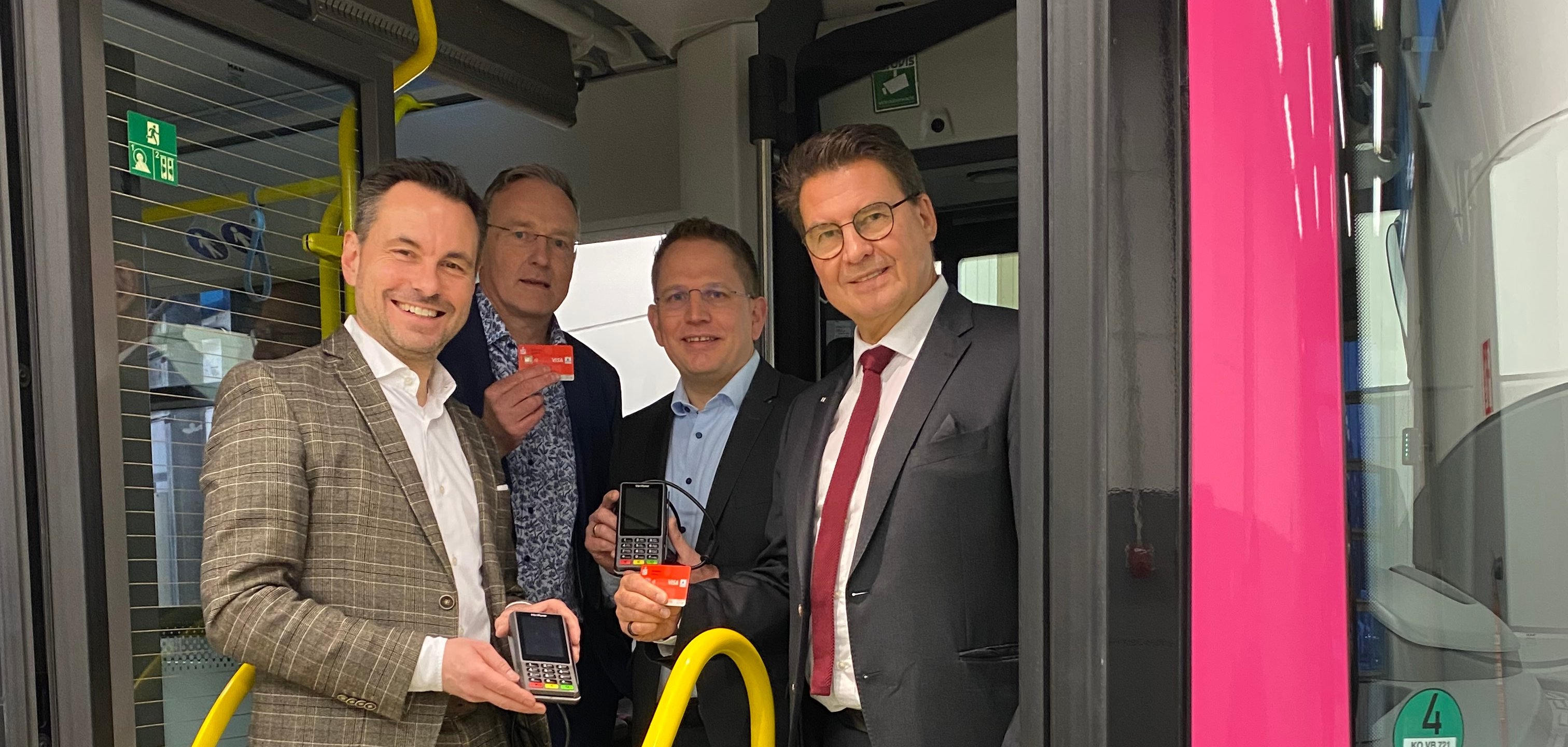 Auf dem Bild stehen Oberbürgermeister David Langner, die koveb-Geschäftsführer Hansjörg Kunz und Lars Hörnig sowie der Vorstandsvorsitzende der Sparkasse Koblenz, Matthias Nester in einem Bus und präsentieren die neuen Cashless Payment Geräte der koveb