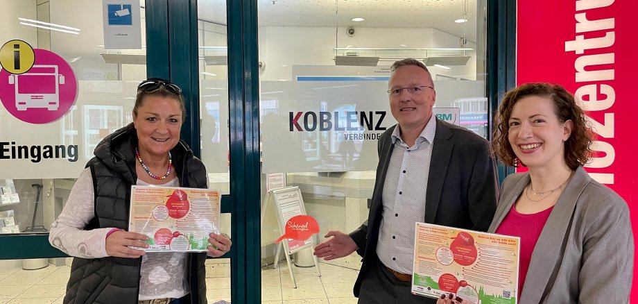 drei Menschen lächeln fröhlich in die Kamera und freuen sich darüber, dass die koveb Schängel unterstützt und dies nun auch am Kundencenter der koveb ausgezeichnet wird