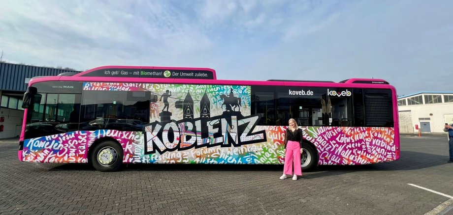 der neu folierte Urban Art-Bus der koveb mit der Designerin der Folierung vor dem Bus