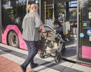 Barrierefreie Haltestelle Mutter mit Kinderwagen steigt barrierefrei in einen Bus ein