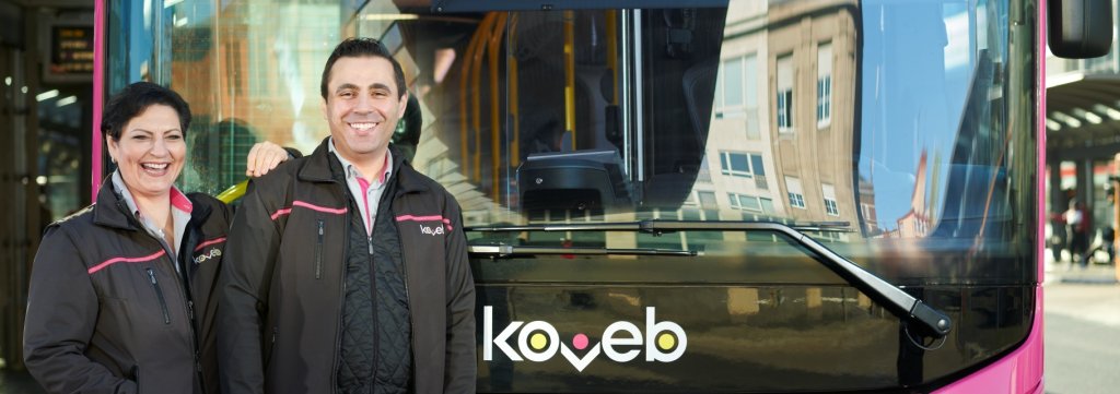 Busfahrerin und Busfahrer lehnen an der Front eines koveb-Busses