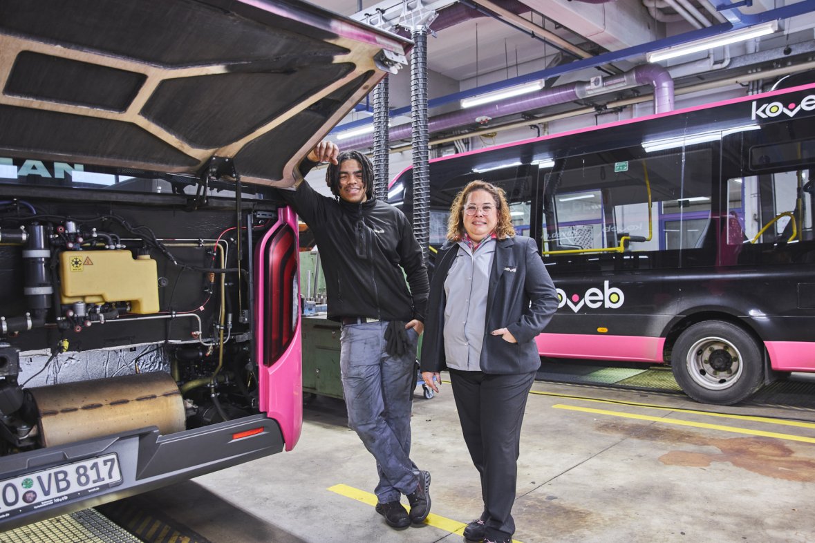 Zwei Beschäftigte der koveb stehen in der Werkstatt vor einem Bus mit offener Motorhaube.