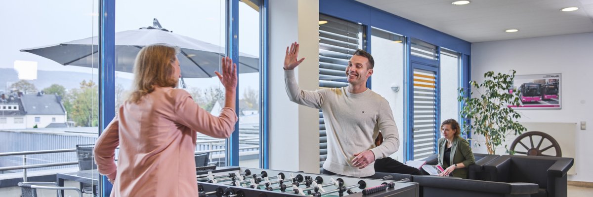 Zwei Mitarbeiter der koveb spielen gut gelaunt Tischkicker