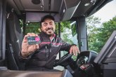 Ein freundlicher Busfahrer der koveb lächelt und hält ein eTicket in die Kamera