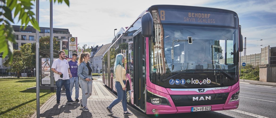 Mehrere Personen steigen in einen Bus der koveb ein.